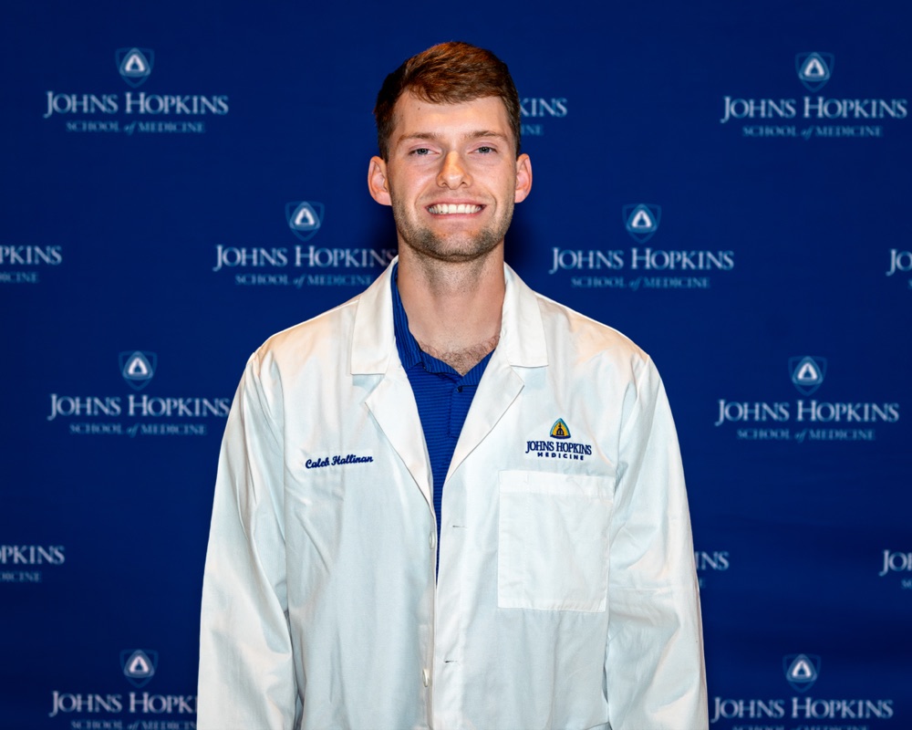 Caleb Hallinan wearing a Johns Hopkins Medicine white coat